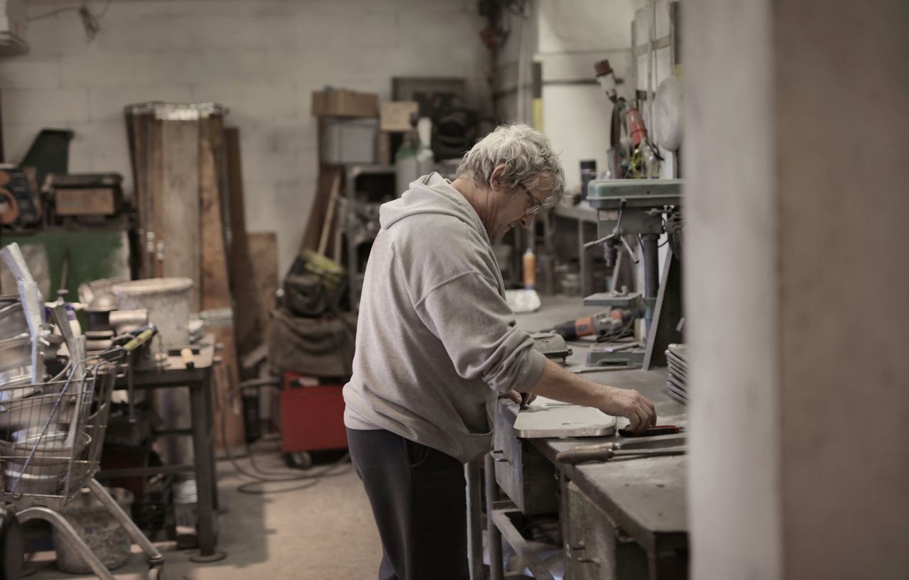 Older man working in cluttered home workshop.