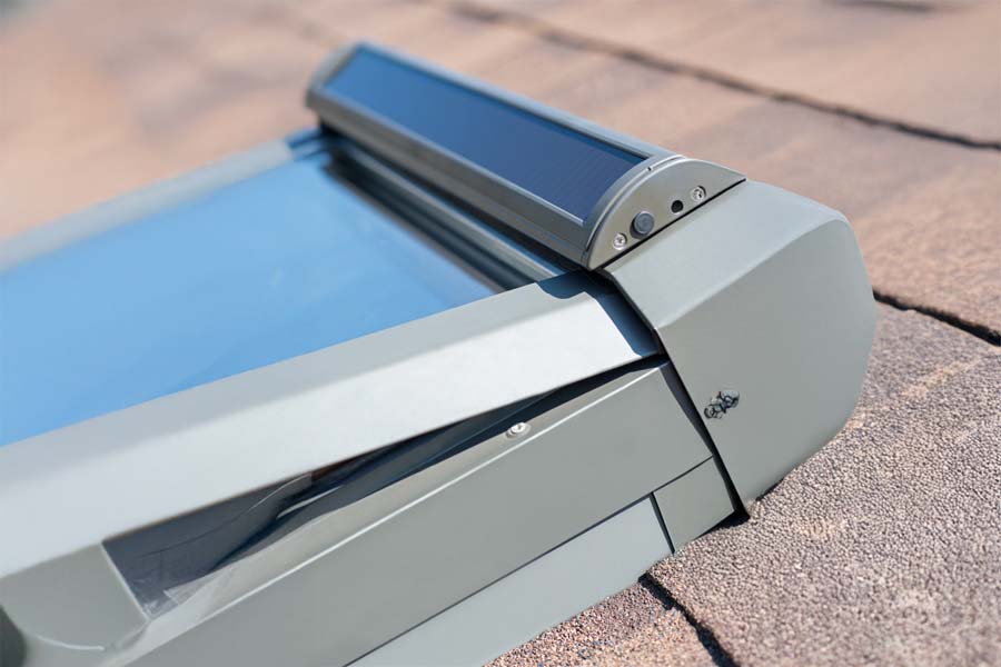 Close-up view of a solar-powered roof window installed on shingle roof