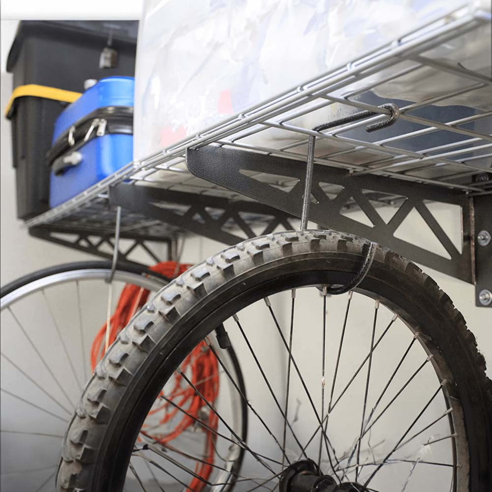 A Bicycle Wheel Hanging From SafeRacks 24 x 48 Wall Shelves Which Is Storing Various Items Like Boxes And A Suitcase