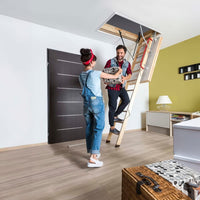 A Man And Woman Are Happily Passing A Box To Each Other As The Man Climbs A Wooden Attic Ladder In A Modern Well-Lit Room