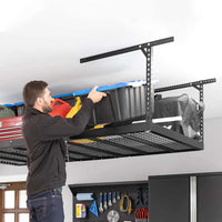 A Man Is Placing A Large Black Storage Bin Onto A 4 Ft X 8 Ft VersaRack Pro Height Adjustable Overhead Rack In Black