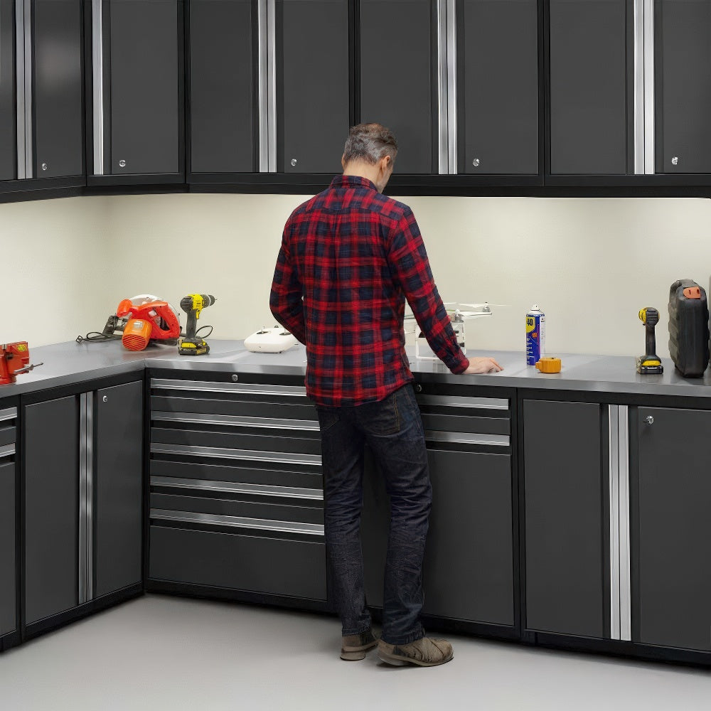 A Man Stands At A Corner Workstation Surrounded By Sleek Black Cabinets And Tools Neatly Arranged On A Stainless Steel Countertop