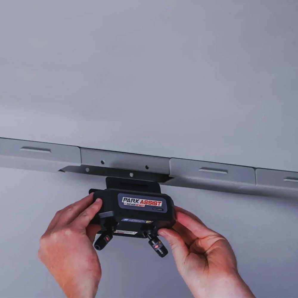 A Person Installing A Black Park Assist Device Onto A Ceiling Track