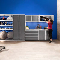 A Woman Reaches Up To Organize Equipment In NewAge Pro Series 42 In Wall Cabinet Containing Various Fitness Items