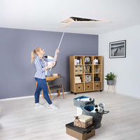 A Woman Uses A Long Pole To Pull Down An Attic Hatch