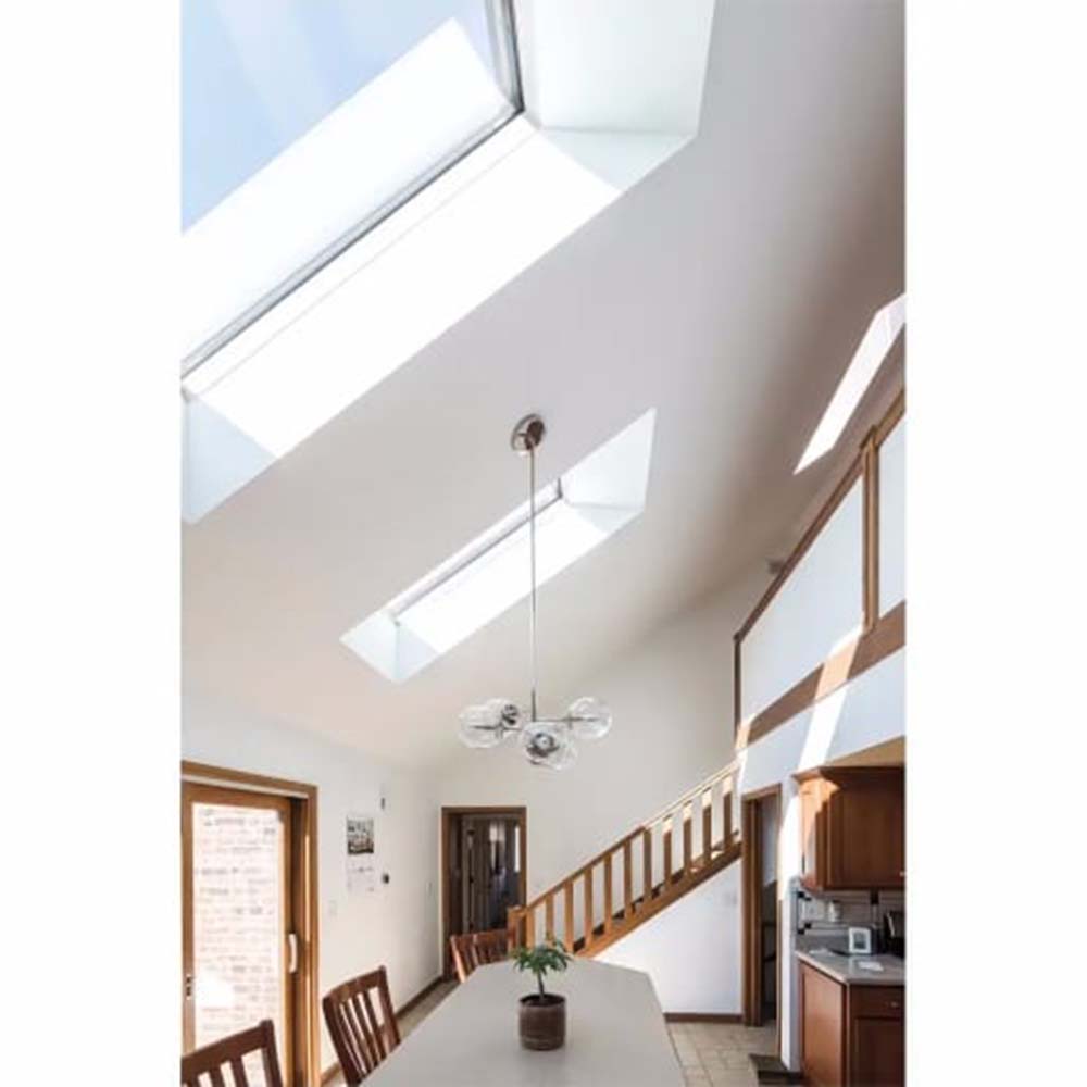 Airy Dining Area With Three Roof Windows Pendant Light Long Table Wooden Staircase And Partial Kitchen View