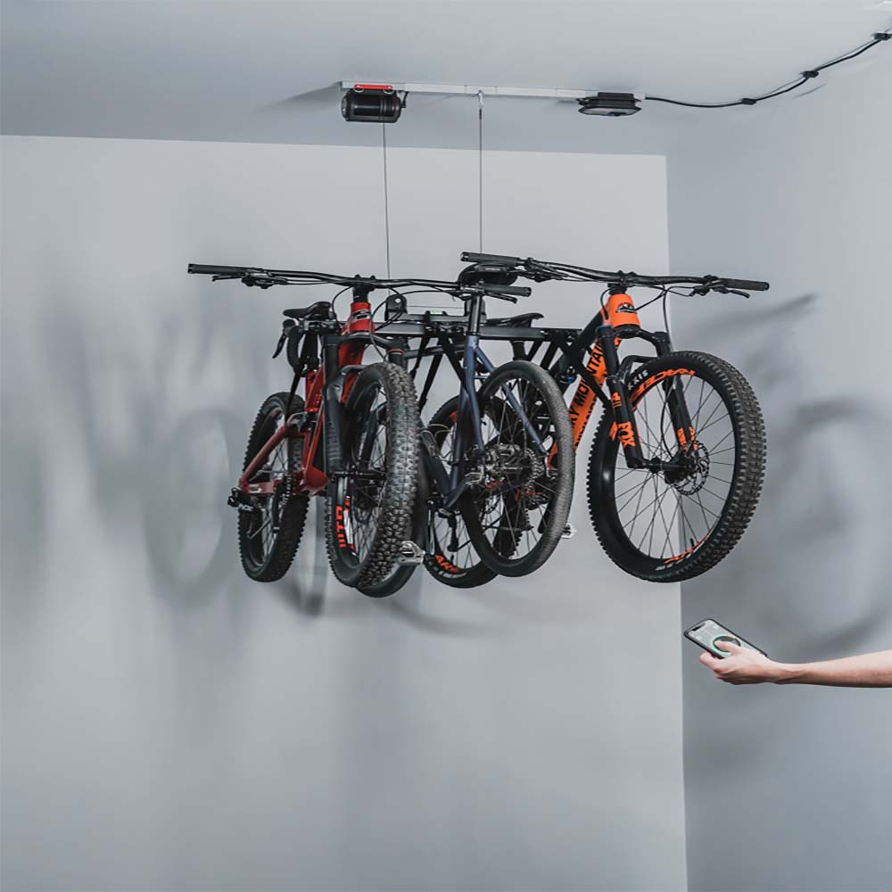 Bicycles Hung From The Ceiling By Bike Hoist By SmarterHome Being Operated By A Person With A Remote Control