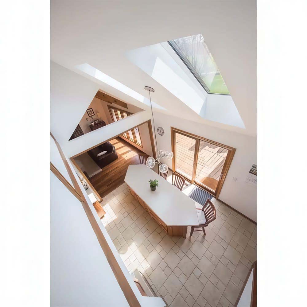 Bright Double Height Dining Area With A Large Roof Window Central Island Sliding Glass Doors And Sunlit Tiled Floor
