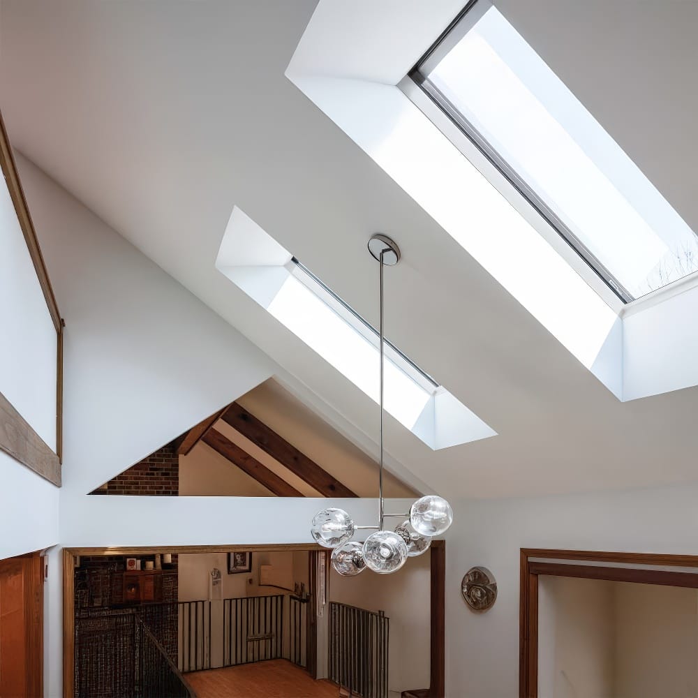 Bright Loft Interior With Slanted Ceiling Showcasing Two Large Skylights And A Modern Glass Ball Chandelier