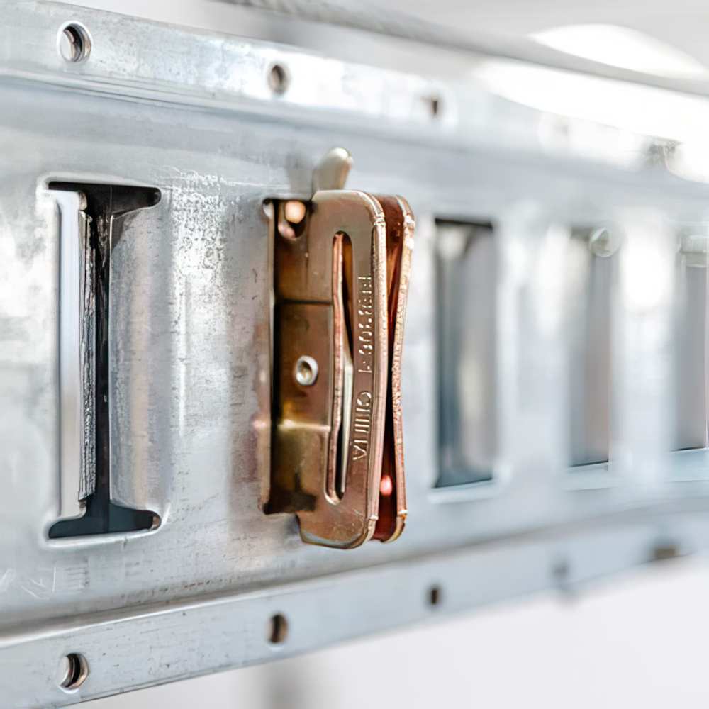 Bronze Colored Carabiner Clamped Onto A Metal Rail With A Series Of Slots