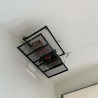 Ceiling Mounted Metal Overhead Storage Rack With Mesh Shelf Holding Boxes And Gear In A Garage