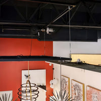 Ceiling Mounted Motorized Hoist System With Cables Suspends Lighting Fixtures Above A Modern Showroom With Red Accent Wall