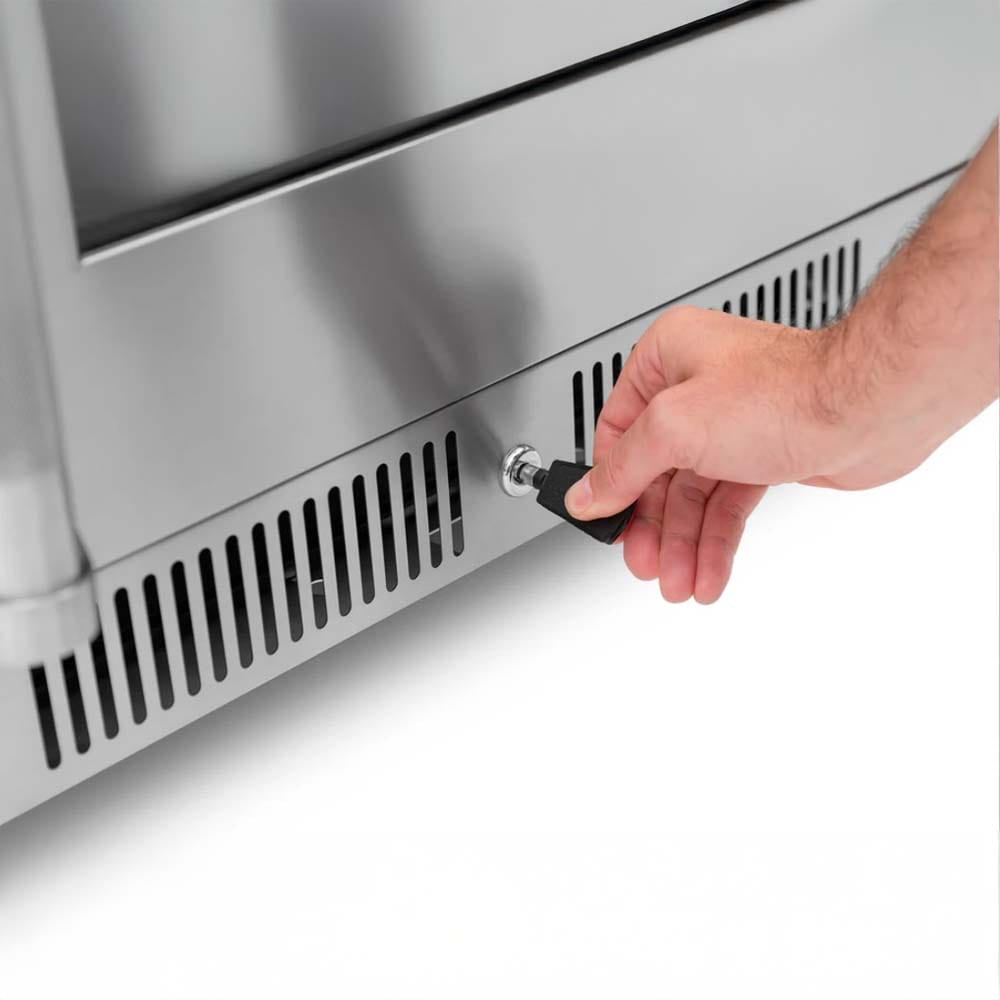 Close-Up Of A Hand Inserting A Key Into The Lock Of A Stainless Steel Beverage Cooler Near Its Bottom Ventilation Grill