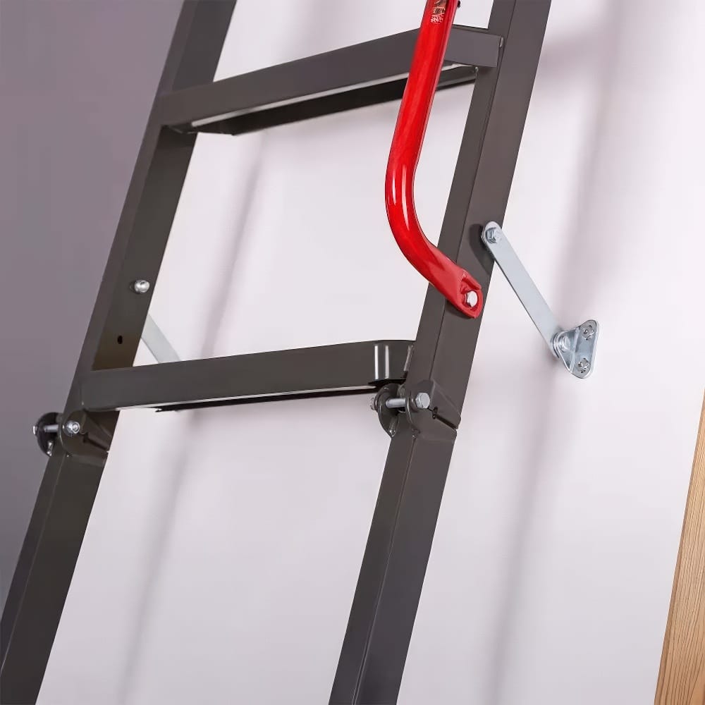 Close-Up Of A Metal Attic Ladder With A Red Handrail And Support Bracket Securely Mounted To A White Access Door
