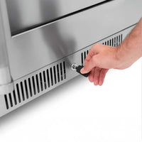 Close-Up Of A Person Inserting A Key Into The Lock Of A Stainless Steel Beverage Cooler Near Its Bottom Ventilation Grill