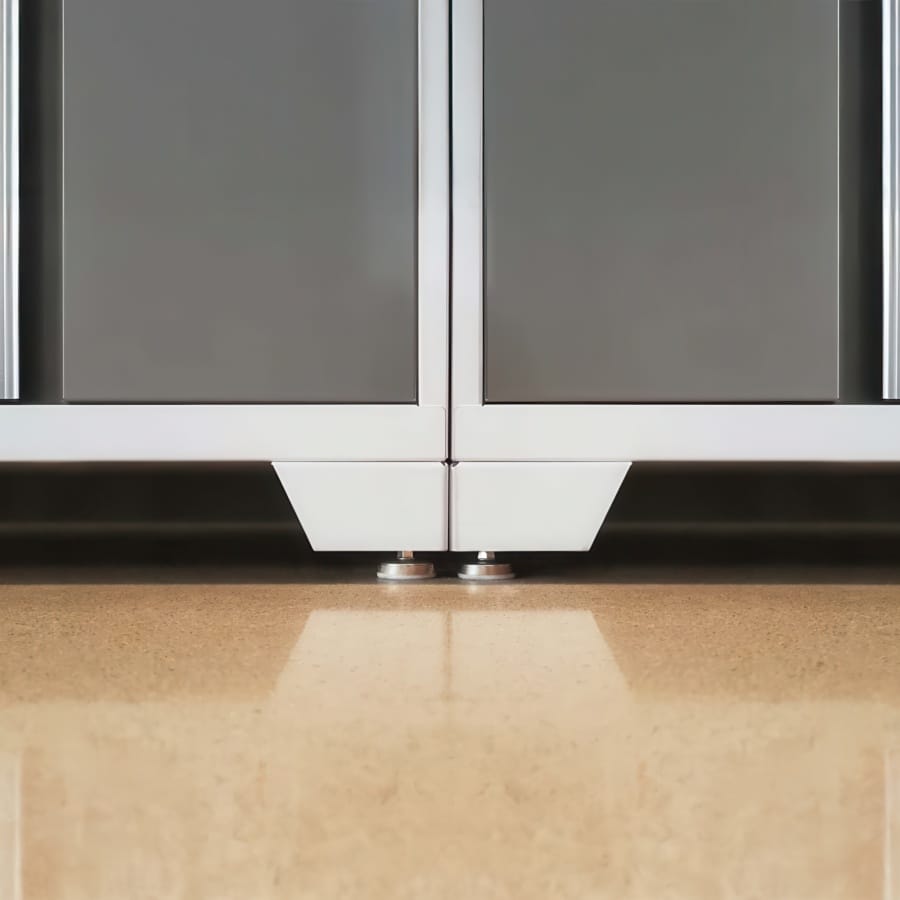 Close-Up Of Adjustable Leveling Feet Beneath Two Gray Garage Cabinets With White Bases On A Polished Floor