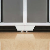 Close-Up Of Adjustable Leveling Feet Beneath Two Gray Garage Cabinets With White Bases On A Polished Floor