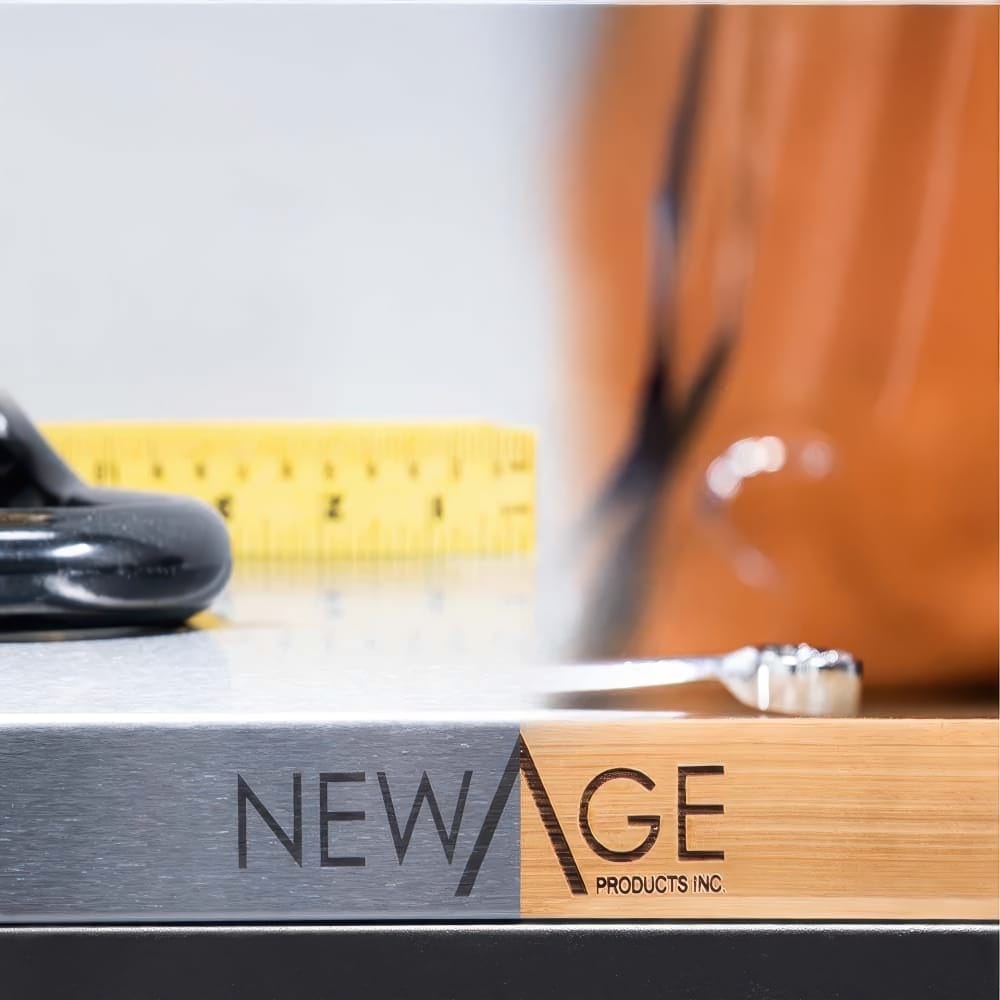 Close-Up Of NewAge Branding On A Stainless Steel And Bamboo Worktop With Tape Measure And Wrench In Background