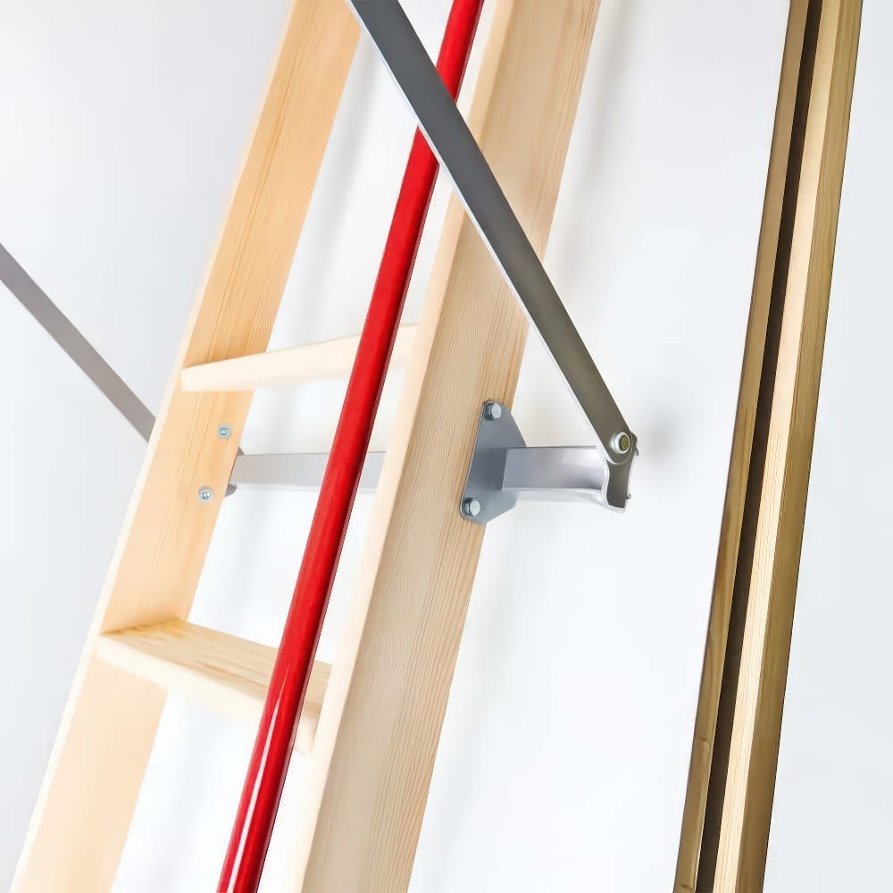 Close-Up View Of A Wooden Attic Ladder With A Red Handrail And Metal Support Arm Securely Fastened To The Frame