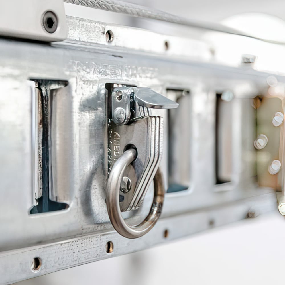 Close Up Of A Metallic Ring And Clasp Mechanism Attached To A Textured Metal Rail