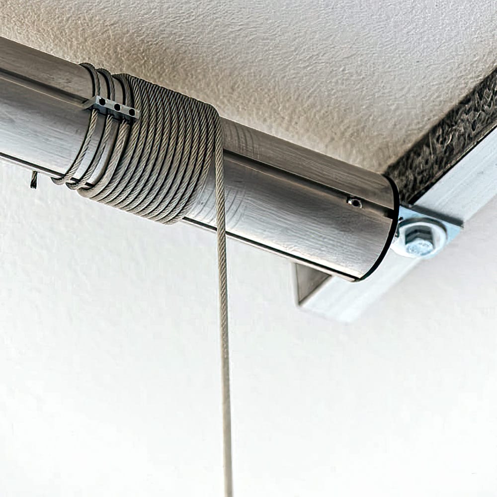 Coiled Metal Cable Wrapped Around A Metallic Rail Secured Under A Textured Ceiling