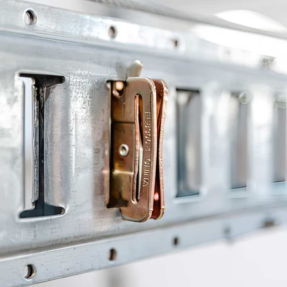 Copper Toned Metal Clasp Attached To A Silver Metallic Rail Part Of AuxxLift Garage Lifter
