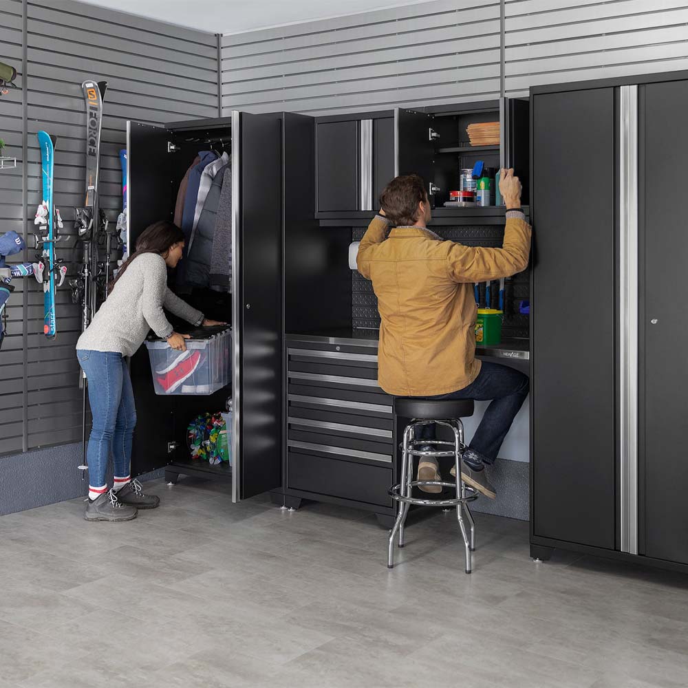 Couple Organizing Gear In Modern Garage With Black Cabinet Storage And Workbench