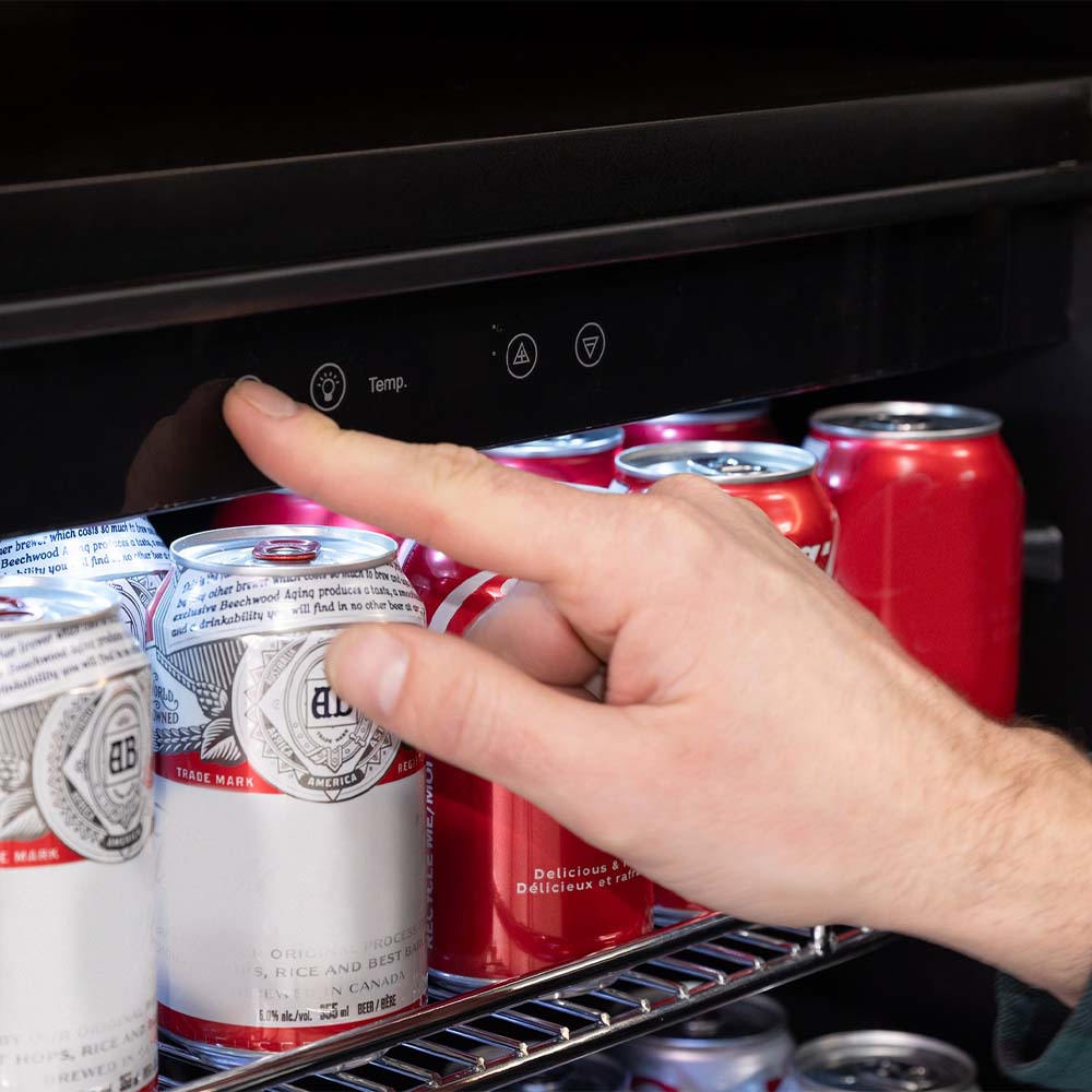 Hand Adjusts Beverage Fridge Touch Controls Above Chilled Soda Cans