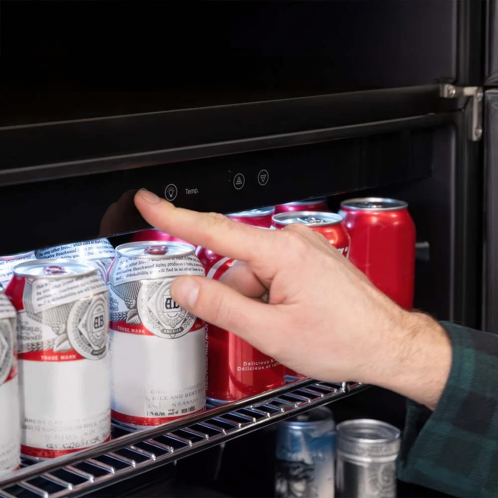 Hand Adjusts Touch Controls On A Beverage Cooler Above Rows Of Soda Cans