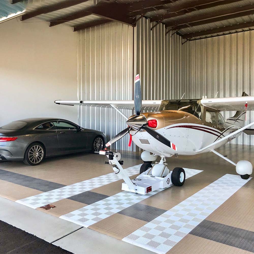 Hangar With A Racedeck Circle Trac Flooring Housing A Small White And Red Propeller Plane On A Wheeled Platform And A Luxury Car