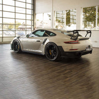Light Silver Car With A Prominent Rear Wing And Black Alloy Wheels Displayed In A Well Lit Showroom And Racedeck Garage Flooring