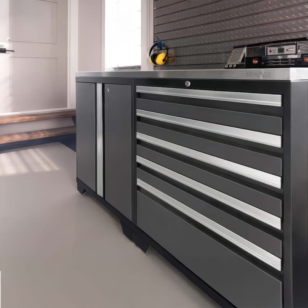 Low Gray Garage Cabinet With Stainless Worktop Featuring A Tall Door Compartment And Six Sleek Drawers Along A Wall Panel