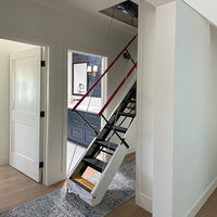 Majic Attic Staircase Extended Down Into A Hallway With A View Into A Bathroom In The Background