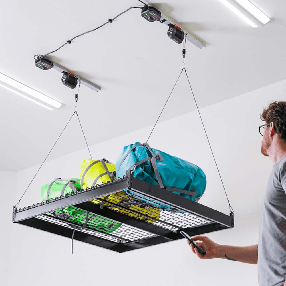 Man Uses Remote To Adjust A Ceiling Mounted Storage Shelf By SmarterHome Motorized Garage Storage Lift Loaded With Gears