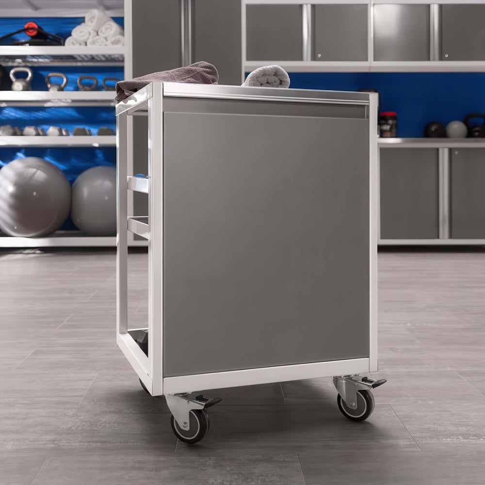 Mobile Gym Service Cart With Towels Sits On Casters In Front Of Gray Storage Cabinets And Exercise Equipment
