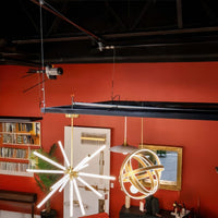 Modern Lighting Showroom With Starburst LED Chandelier And Glowing Orb Pendant Suspended Below A Ceiling Rig And Red Accent Wall
