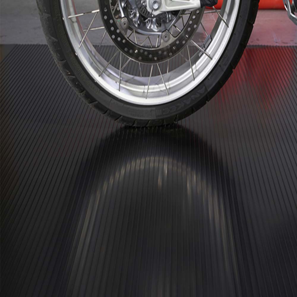 Motorcycles Front Wheel Featuring A Silver Spoked Rim Resting On A Ribbed Black G-Floor Garage Flooring