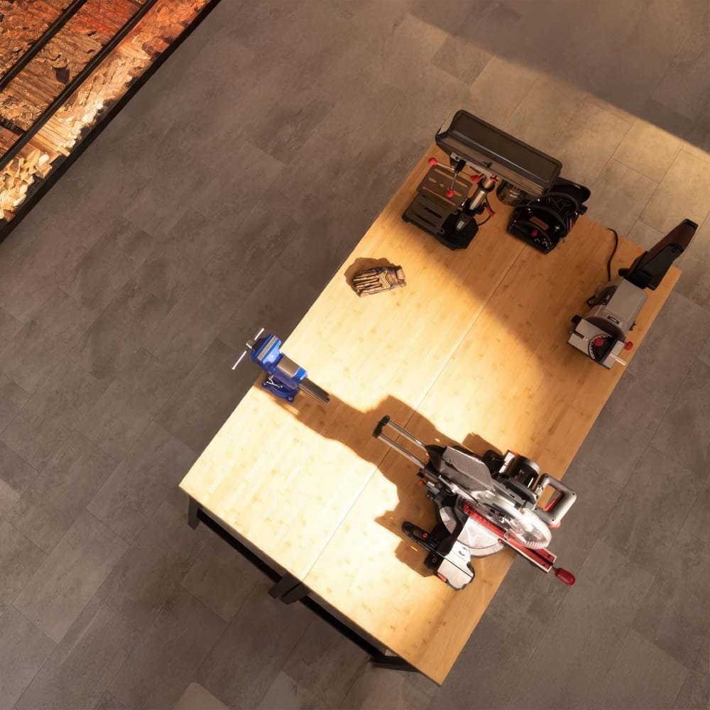 Overhead View Of A Bamboo Workbench With Miter Saw Drill Press Vise Gloves And Power Tools On A Gray Tile Floor In A Workshop