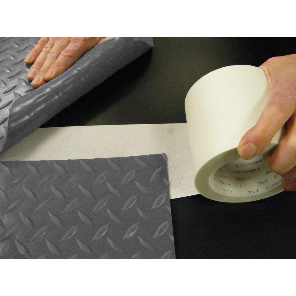 Pair Of Hands Are Shown Applying A White Adhesive Tape For Roll-Out Mats With A Diamond Plate Pattern