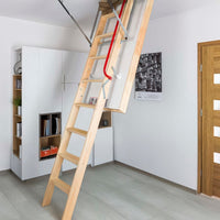 Partially Extended Wooden Attic Ladder With A Red Safety Handrail Installed In A Modern Neatly Organized Room