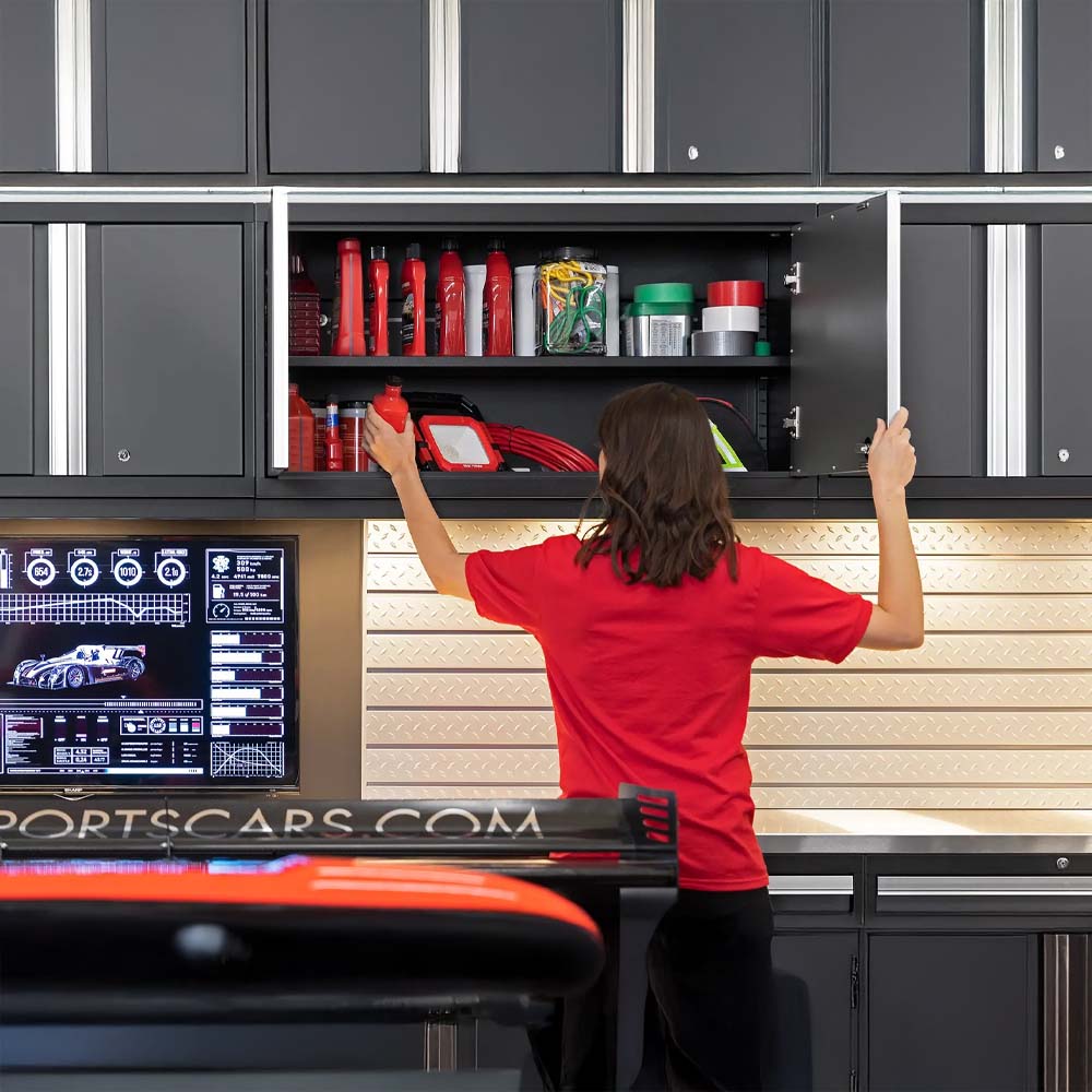 Person Organizing Supplies In Overhead Garage Cabinet Above Racing Workstation
