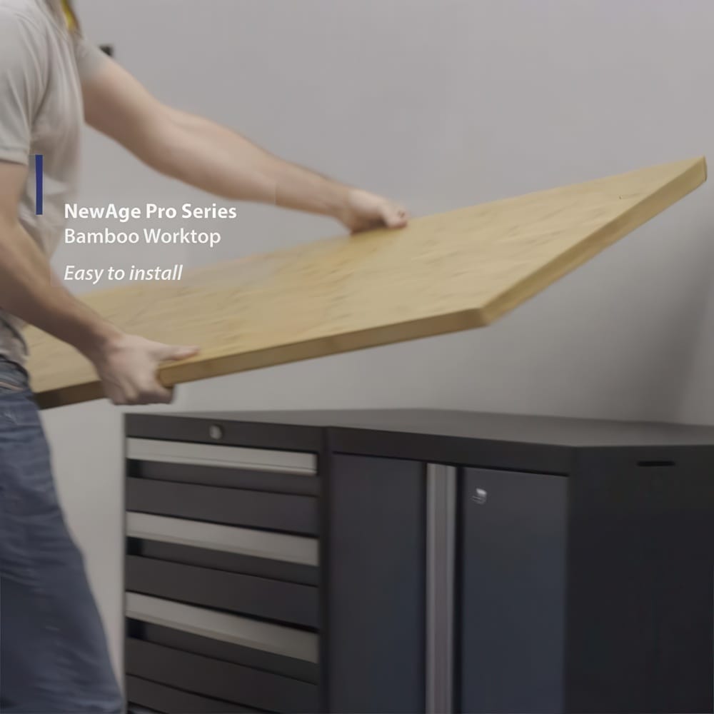 Person Placing A Bamboo Worktop Onto Black Garage Cabinets