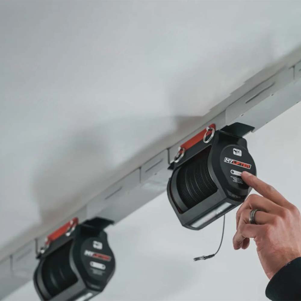 Person Pressing A Button On Wall Mounted SmarterHome Fifth Wheel Lifter That Is Attached To A Rail Mounted To The Ceiling