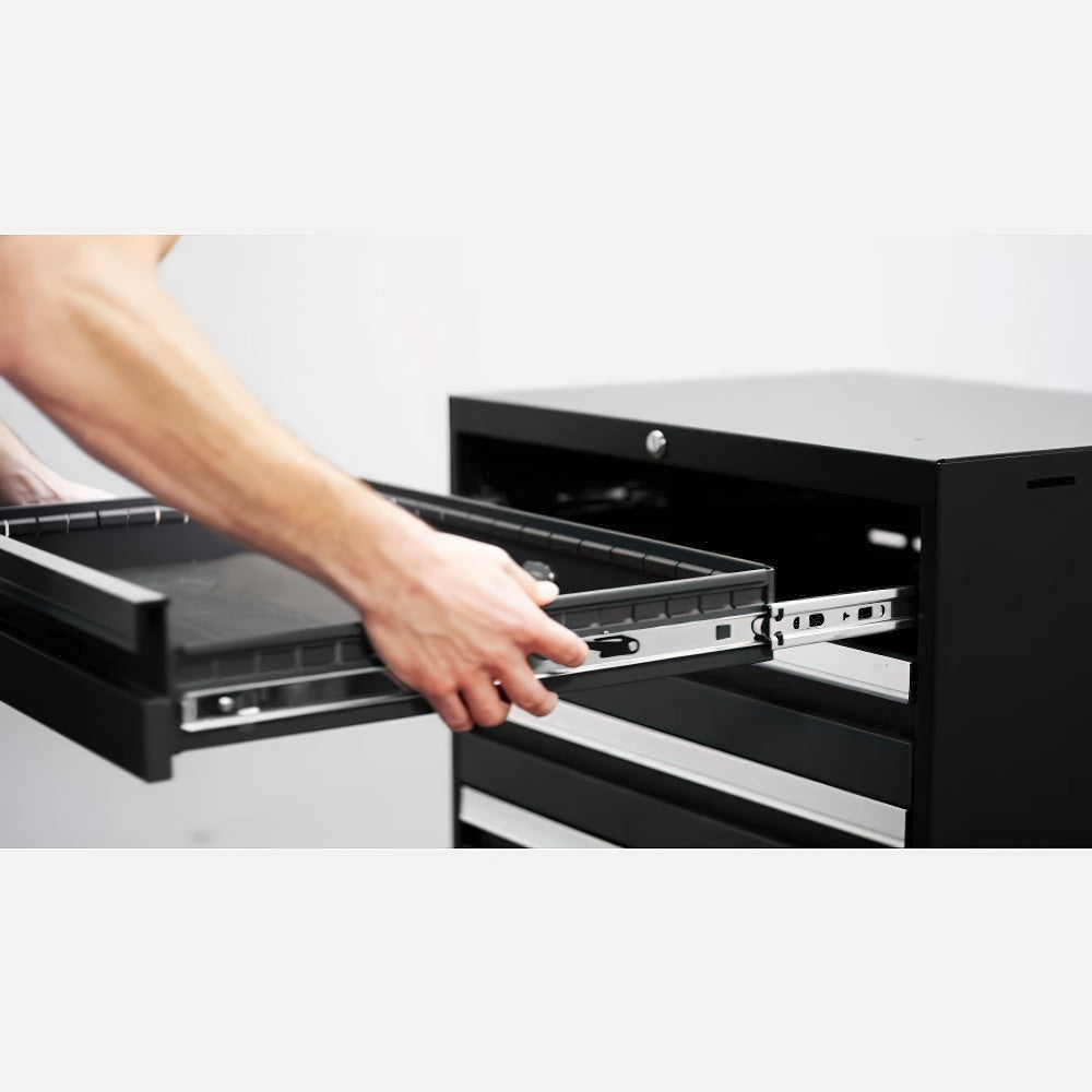 Person Reinstalling A Black Drawer Onto Its Metal Sliding Tracks In A Black Cabinet With Chrome-Accented Drawers