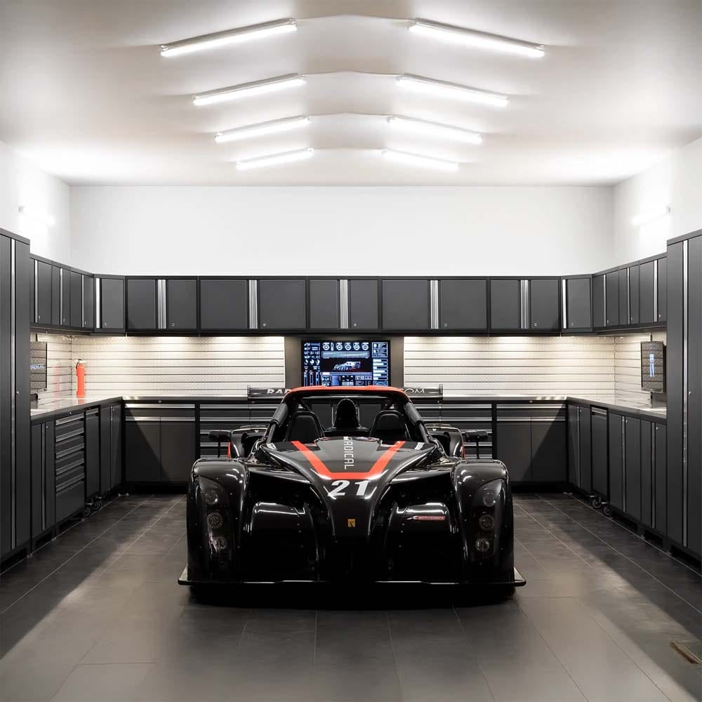 Race Car Parked In Sleek Garage Surrounded By Dark Cabinets And Bright Overhead Lighting