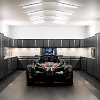 Race Car Parked In Sleek Garage Surrounded By Dark Cabinets And Bright Overhead Lighting