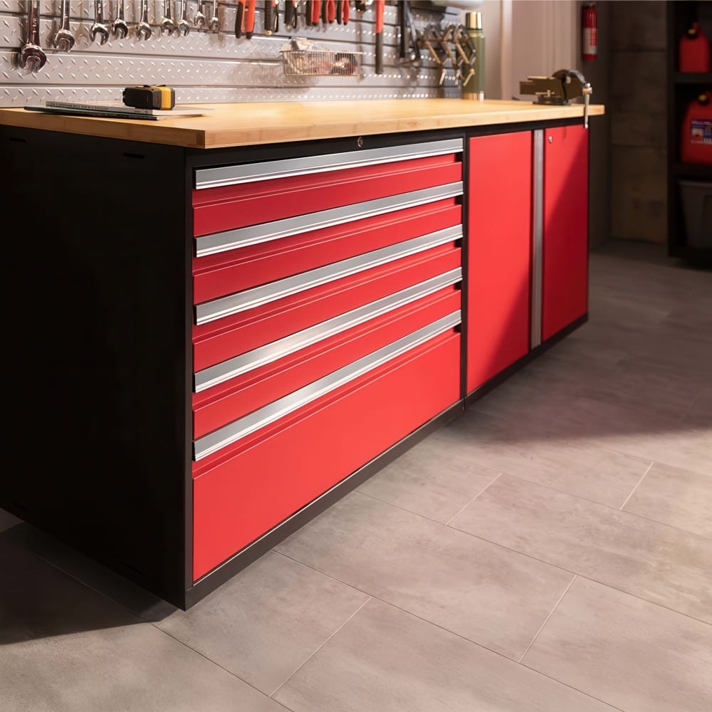Red Garage Workbench With Wood Top And Wide Tool Drawers Below A Wall Of Hanging Hand Tools