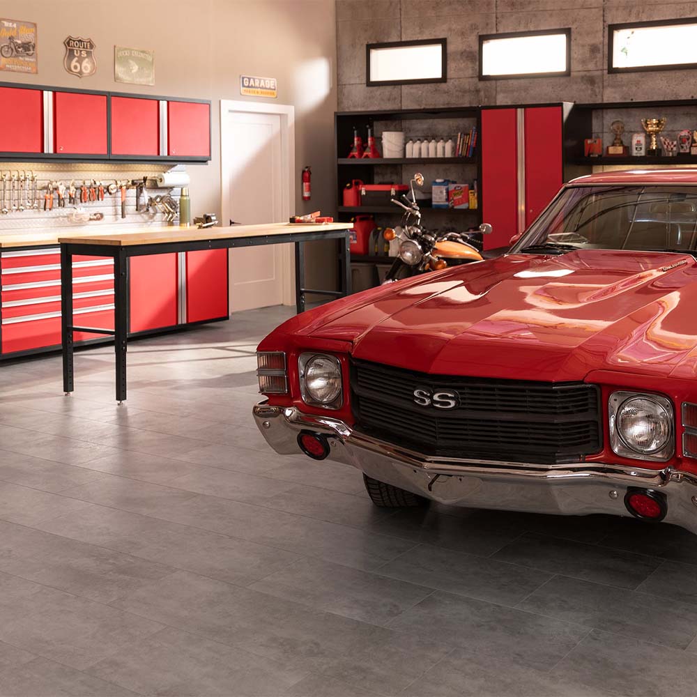 Red Muscle Car Parked In A Garage With Red Tool Cabinets Workbench And Wall Mounted Signs In The Background