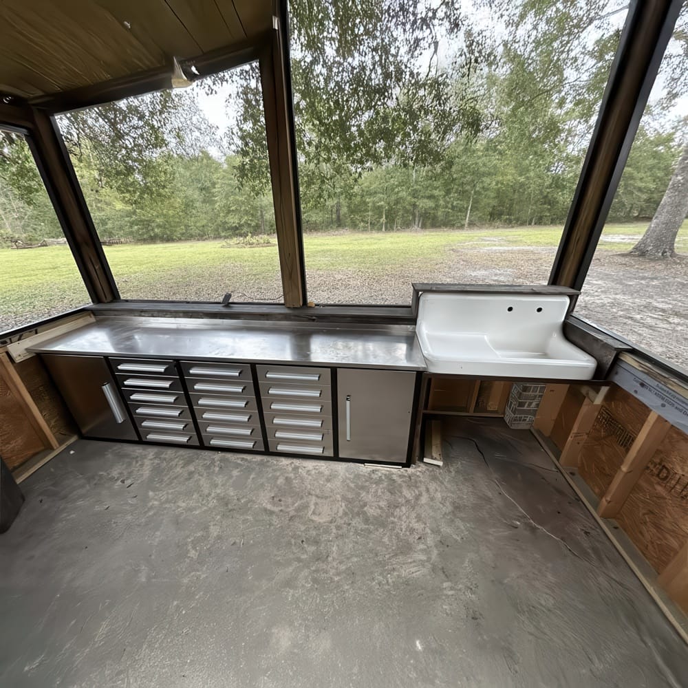 Screened Porch Work Area With Stainless Steel Countertop Drawer Cabinets And A White Utility Sink