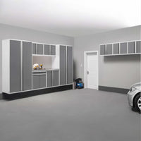 Spacious Garage Featuring White Frames With Gray Cabinets A Lit Work Nook Wall Mounted Upper Units A Door And A Silver Car In View